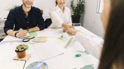 Two businesswoman shaking hands over desk in office