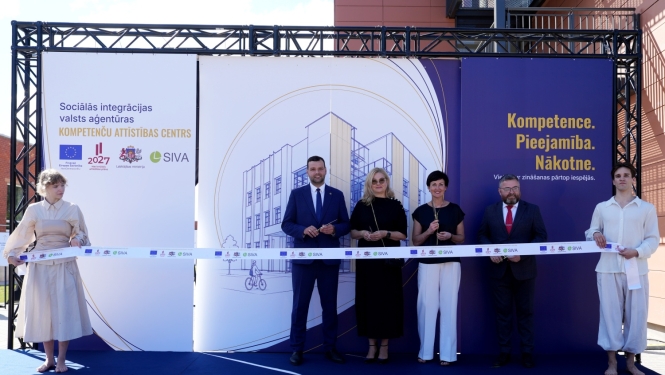Jūrmalā atklāts Sociālās integrācijas valsts aģentūras Kompetenču attīstības centrs. Uz skatuves seši dalībnieki piedalās simboliskajā lentes griešanas ceremonijā. Fonā izvietots centra vizuālais noformējums ar ēkas attēlu un uzrakstu “Kompetence. Pieejamība. Nākotne.”