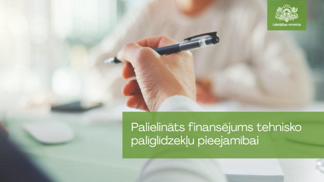 Tuvplānā redzama roka, kas tur pildspalvu konsultācijas vai dokumentu aizpildīšanas laikā. Attēla apakšējā daļā izvietots uzraksts “Palielināts finansējums tehnisko palīglīdzekļu pieejamībai”, augšējā labajā stūrī – Labklājības ministrijas logotips. Fona attēls ir izpludināts, radot biroja vai konsultāciju vides iespaidu.
