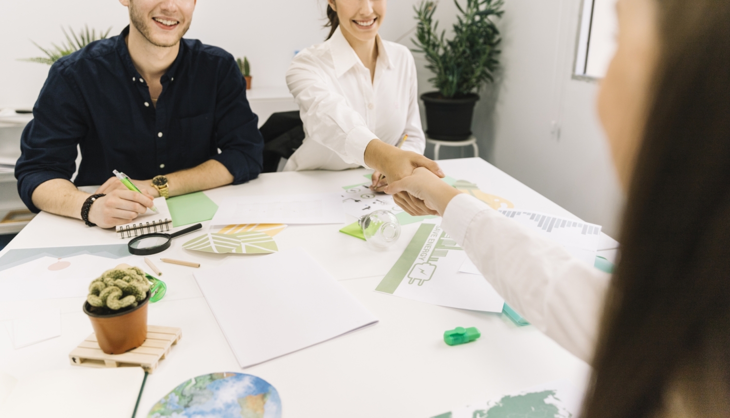 Two businesswoman shaking hands over desk in office