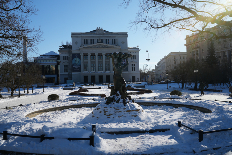 Foto redzama Nimfas strūklaka un aizmugurē Nacionālā operas ēka, sniegaina diena