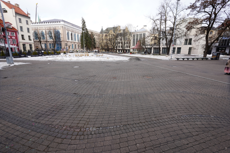 Foto redzams Vecrīgas centra laukums, bruģis un ēkas fonā., Saucās Noslēpumainā upe zem bruģa