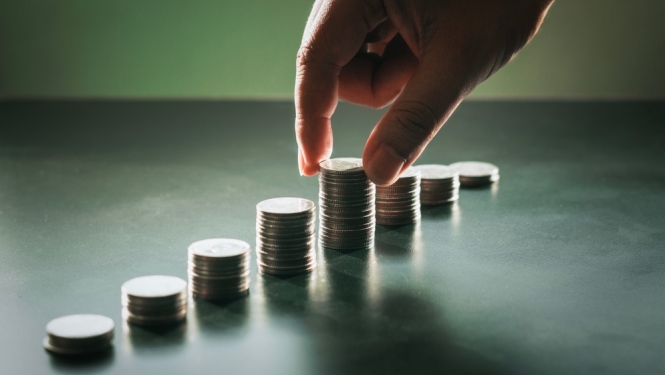 Euro monētas salikas kaudzītēs un bildē roka cilā monētiņas