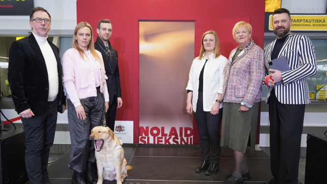 Kampaņas "nolaid slieksni" bilde pēc pasākuma atklāšanas. Bilde visi dalībnieki, pasākuma vadītājs, fonā kampaņas baneris ar durvīm