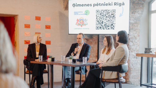 kampanas mazie mirkli atklāšanas pasākums. Runātāji un vadītājs sēž pei galda, runājas un aizmugure prezentācija  redzama.