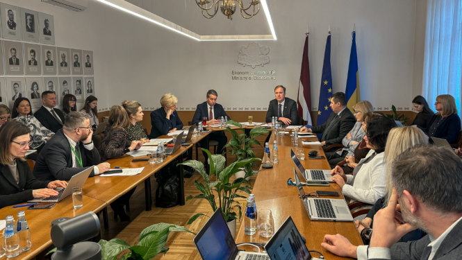 sēde cilvēki pie galda fonā karogi uzraksts ekonomikas ministrija