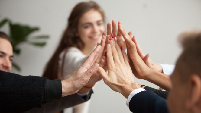 cilvēki saliek kopā rokas, attēlo ka kopā sadarbojas