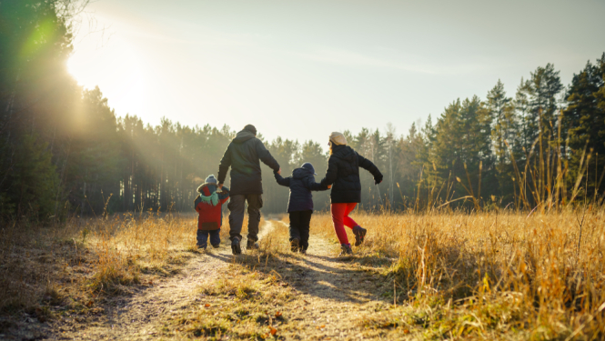 bilde kur ģimenes ar diviem bērniem skrien sadevusies rokās , bilde no mugurpuses