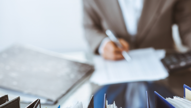 vīrietis sēž pie galda ar dokumentiem un tos paraksta. ilutratīvs attēls