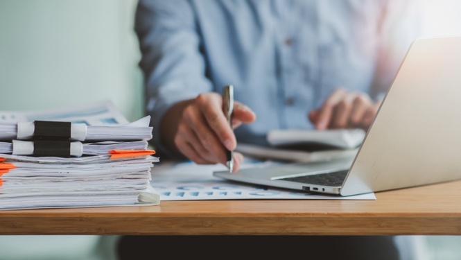 Strādā pie datora ar dokumentu kaudzi