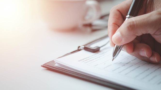 paraksta dokumentus, bilde redzama roka, kurai rokās pildspalva un raksta uz lapas