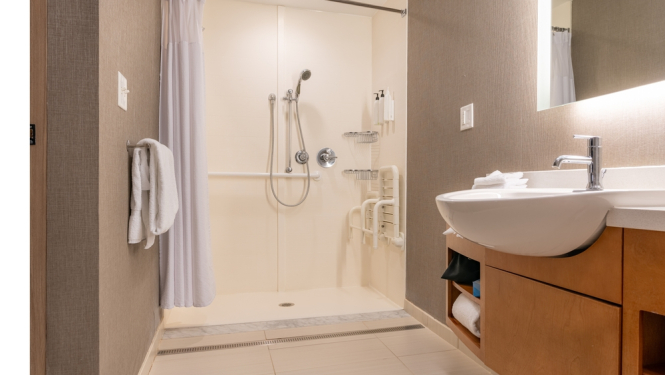 attēlota vannasistaba cilvēkam ar invaliditāti ratiņkreslā, dušas telpa aprikota