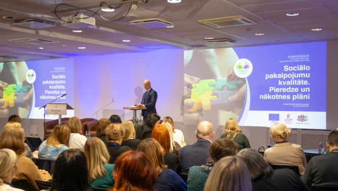 konferences noslēguma diskusija sēž skatītāti un priekšā stāv runātājs, kuram aizmugurē prezentācija