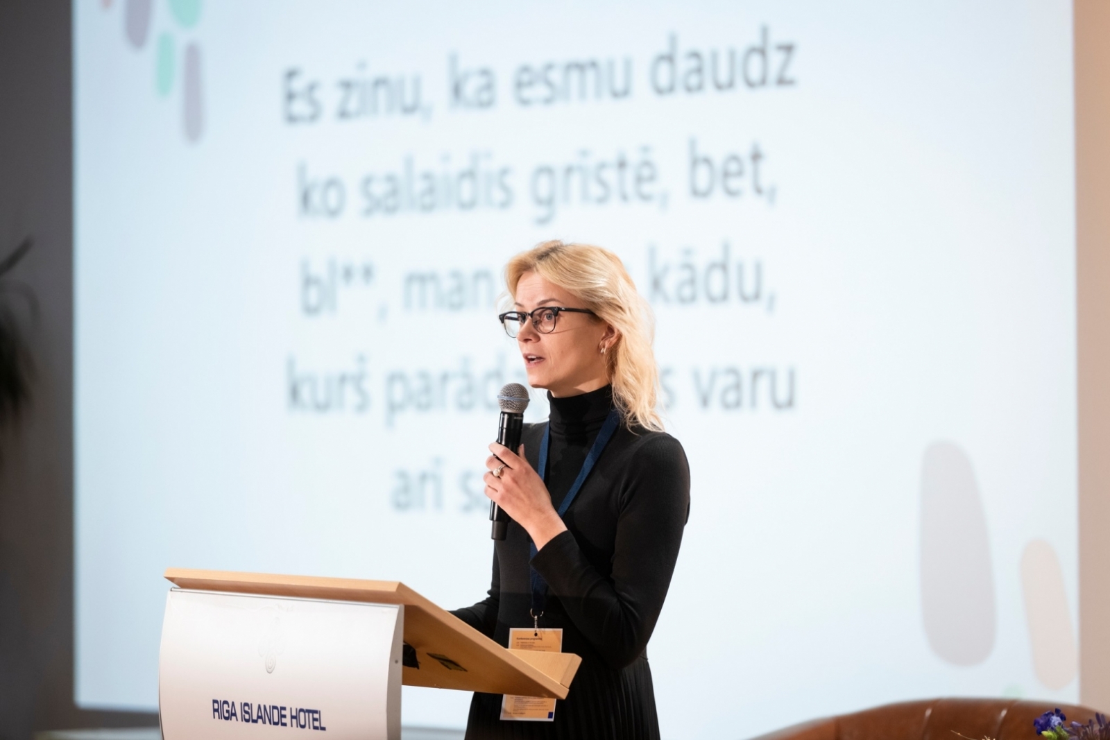 Konferences norise — prezentētāja ar mikrofonu