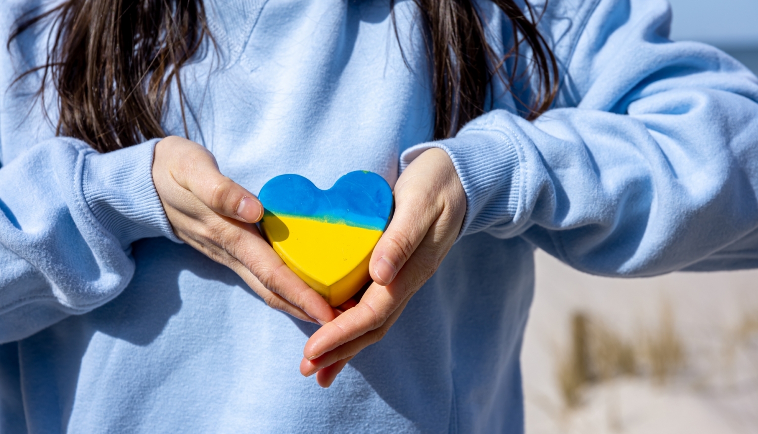 Sieviete rokās tur dzeltenas un zilas krāsas sirds formu 